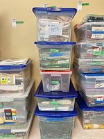 Stack of clear plastic bins labeled batik greens neutrals and misc fabrics