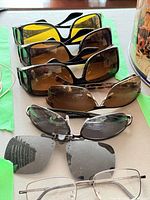 Six pairs of sunglasses and one eyeglass laid out to show styles and lens colors