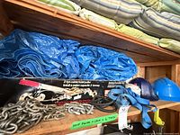 Overall lot on shelf showing hoist box, chain, tarps, straps