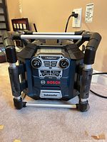 Front view of Bosch PB360C-C radio showing control panel, LCD, roll-cage frame