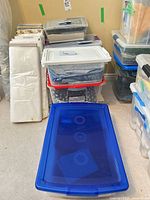 Stack of clear and opaque storage totes containing folded fabric pieces