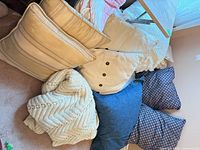 Group of pillows, throws visible together on floor