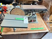 Front view of Delta belt/disc sander on wood base with worktable and maxsold label
