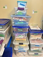 Stacked clear totes with blue lids labeled cotton, contents visible