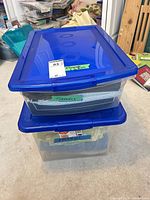 Two clear plastic bins with blue lids containing flannel fabric pieces