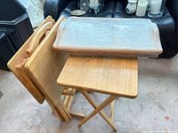 Folded wooden TV trays in stand next to wrapped serving tray