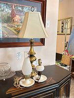 Both lamps on tabletop: brass lamp with shade; hobnail milk glass hurricane lamp with cord and chimney