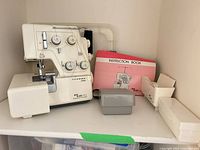 Serger with cover sections, manual, accessory boxes on shelf