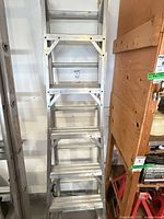 Folded aluminum extension ladder front view leaning against wall