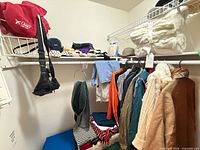 Full closet view showing sweaters, jackets, scarves, handbag, folded throws