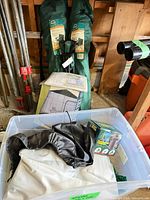 Plastic bin holding boxed air mattress, boxed pump, folded mattress, patio cover and chair bags