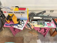 Overview showing laser level kit case, vise, angle gauge, tile spacers on bench