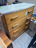 Front and side view of light brown 4-drawer wood dresser wrapped in plastic film