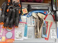 Overview of packaged clamps, Little Wizard detector, Delta piece, drill gauge, locking pliers and assorted small packaged hardware on table