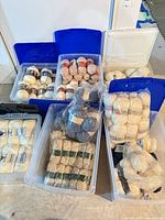 Multiple clear bins with blue lids filled with assorted cream and blue bulky yarn skeins