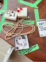 Overview of lot showing faux pearl necklaces, enamel lips brooch, cross pendants, assorted jewellery boxes