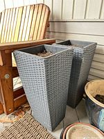 Pair of gray wicker-look resin planters beside chair