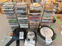 Overall lot with electronics, carrying case, cables and two tall CD racks filled with discs