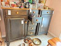 Front view of black sideboard showing doors, drawers, wood top and hardware