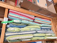 Rack holding one red striped cushion and multiple green/blue cushions
