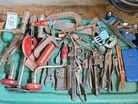 Overall view showing majority of assorted tools on green surface
