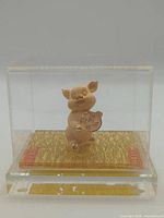 Front view of gold-plated pig figurine inside acrylic case