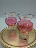 Pair of cranberry glass vases on tray showing shape and color