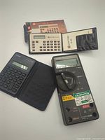 Front view showing Fluke 75 multimeter, Ceptre SL-135 calculator with booklet, Canon LD-35 calculator