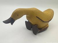front three-quarter view of carved yellow wooden duck with brown beak and feet