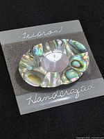 Front view showing abalone and mother-of-pearl oval brooch on display card