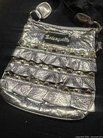Front view showing silver metallic bag with rows of gold-tone studs and logo plaque