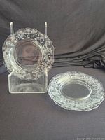 Two of the clear glass etched plates, one upright showing pattern, one flat