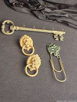 Full view of oversized key wall hook, two lion head knockers, frog plaque