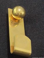 Front view of gold-tone brass lapel pin showing spherical accent and clip hook