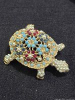 Front view of turtle brooch showing faux pearls, turquoise cabochons, red and blue rhinestones
