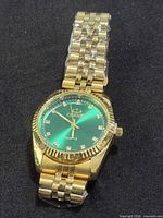 Front view showing green dial, crystal markers, gold-tone case and bracelet