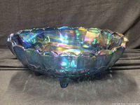 Side view showing scalloped rim, iridescent surface and three feet