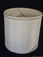 Overall view of ivory fabric drum lampshade with gold trim