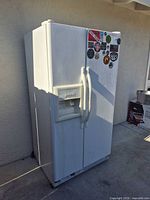 Full left-angle view of Kenmore side-by-side refrigerator placed outdoors