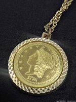Close-up of gold-tone coin-style pendant showing Leo side and textured border