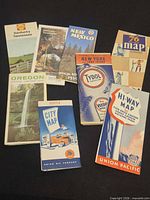 Group shot of all nine folded maps and brochures laid out on black background