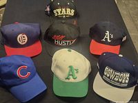 Seven snapback caps displayed on black surface
