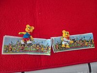 Two small yellow bear figurines with paper backdrops