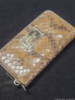 Full view of wallet front showing embossed leather pattern and logo plate
