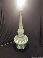 Full lamp illuminated showing ceramic body, metal base, cord