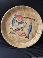 Full view of round wood-veneer tray with fish illustrations