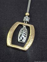 Full view of pendant showing gold-tone hammered frame and inner silver-tone floral drop