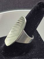 Angled view of ring showing oval ridged face and silver tone
