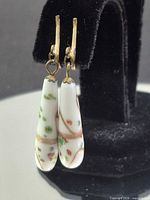 Front view of porcelain floral drop earrings on stand