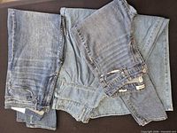 Three folded pairs blue jeans on dark surface